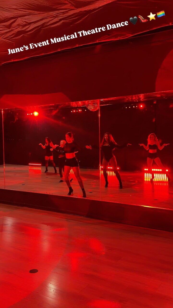 Dancers in black reflected in studio mirrors under red light